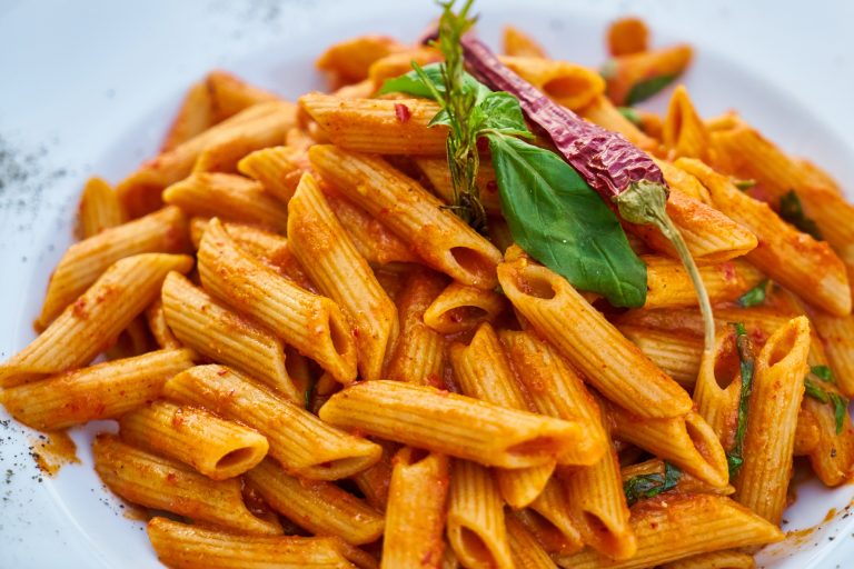 Un piatto estivo di pasta vegana: penne con funghi, panna vegetale, zafferano e noci