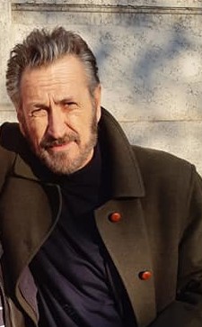 L’eredità di Rocco Schiavone: solitudine e redenzione | Analisi

La terza stagione di “Rocco Schiavone” esplora le profondità della sofferenza umana e della solitudine con la stessa intensità e cinismo del personaggio interpretato da Marco Giallini. Fedele all’opera di Antonio Manzini, la serie mantiene il suo fascino, nonostante un leggero calo degli ascolti rispetto alle stagioni precedenti.  La location suggestiva di Aosta fa da sfondo alle indagini del vicequestore, il cui dolore per la perdita della moglie Marina (Isabella Ragonese) è palpabile in ogni episodio. I quattro episodi ci immergono nell’infelicità di Schiavone, culminando in un finale aperto che promette una quarta stagione ricca di eventi (già annunciata nel 2020).  Malgrado le difficoltà narrative, gli oltre due milioni di spettatori confermano il successo della serie, coprodotta da Rai, Beta Film e Cross Productions.  L’umorismo derivante dalle interazioni con i suoi stravaganti colleghi contrasta con la profonda sofferenza di Schiavone, una sofferenza che pochi riescono a comprendere appieno. In questa stagione, la moglie defunta diventa una figura quasi accusatoria, proiettando un’ombra sulla vendetta del marito contro Baiocchi, l’assassino di Marina.  L’amara verità, rivelata nell’ultima puntata del 23 ottobre, è che “le scelte le decidiamo noi stessi”, parole che risuonano nel percorso di redenzione, o forse di accettazione, del protagonista. Schiavone, nonostante il suo dolore, offre protezione e consigli a chi lo circonda, da Italo Pierron (Ernesto D’Argenio), alle prese con la ludopatia, al giovane Gabriele (Carlo Ponti di Sant’Angelo) e alla giornalista Sandra Bucellato (Valeria Solarino).  La narrazione si concentra sui mali della società contemporanea: la solitudine, lo sfruttamento e la disperazione, rappresentati da diverse vicende, dal furto di opere d’arte alla lotta per la sopravvivenza tra senzatetto, fino al dramma della dipendenza dal gioco d’azzardo.  Il giudizio complessivo è positivo, e ci si chiede quale impatto avrebbe avuto la serie se fosse stata trasmessa su Rai 1.